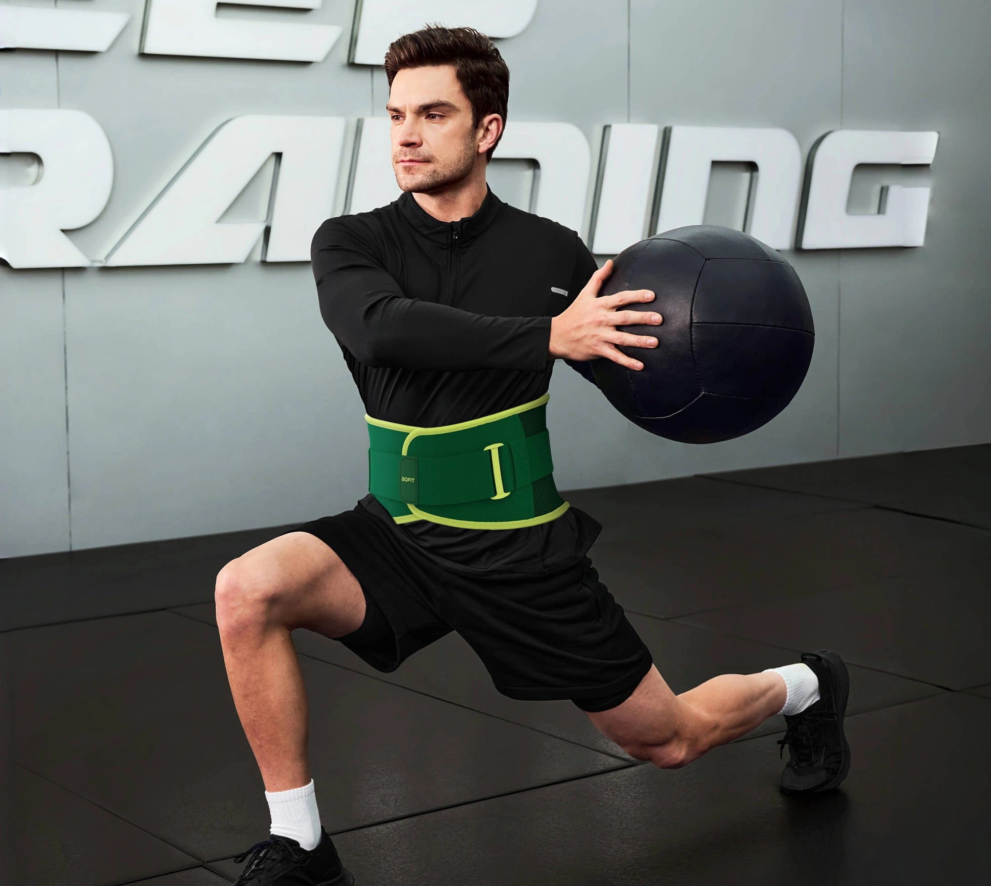 Man wearing gym belt exercising with a medicine ball in a gym setting